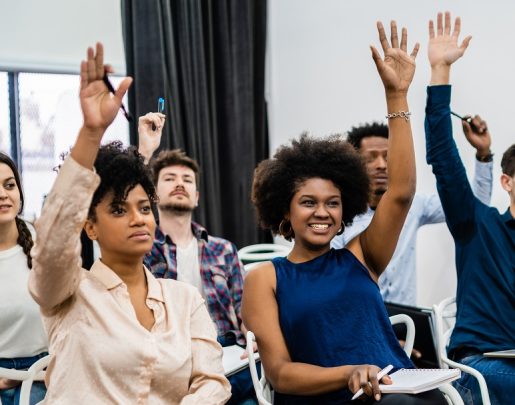 Group of young people sitting on conference together while raising their hands to ask a question. Business team meeting seminar training concept.